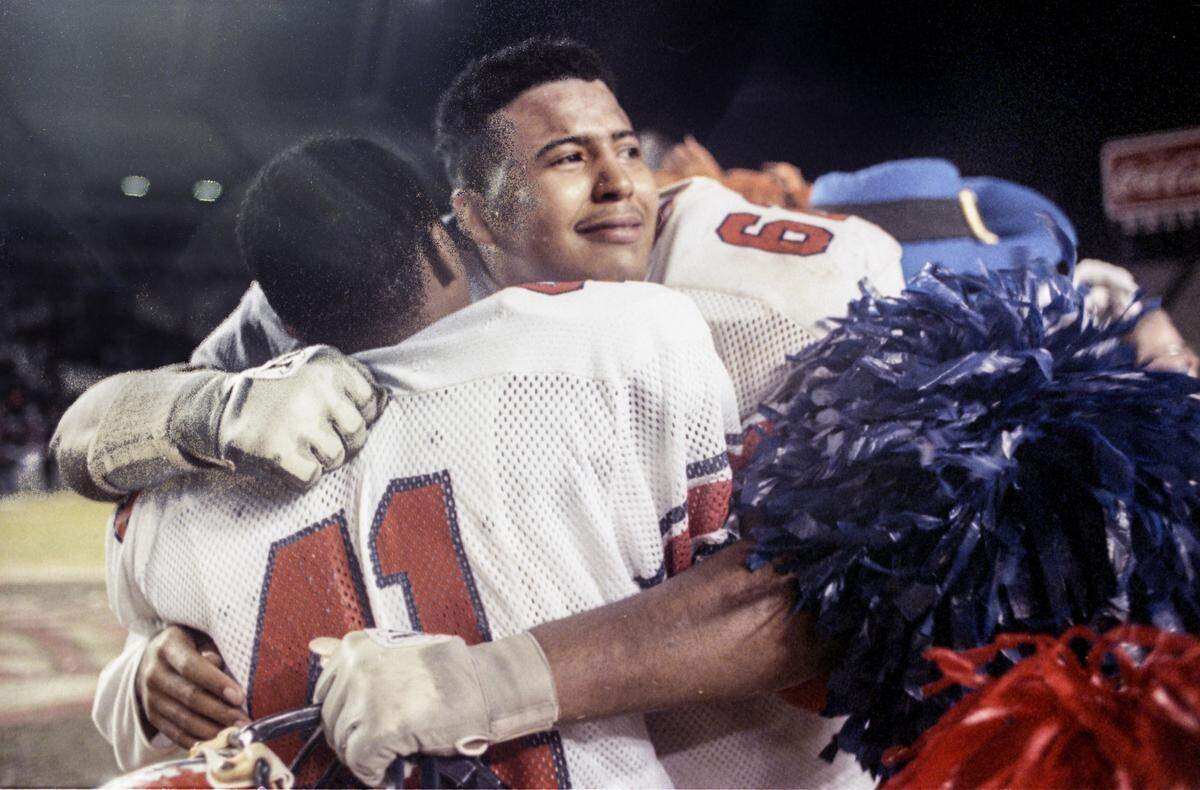 Freddie Solomon, back to camera, hugs a teary-eyed Jerrell Moore as Richland Northeast High School defeated Hartsville 30-24 in the 1993 state championship.