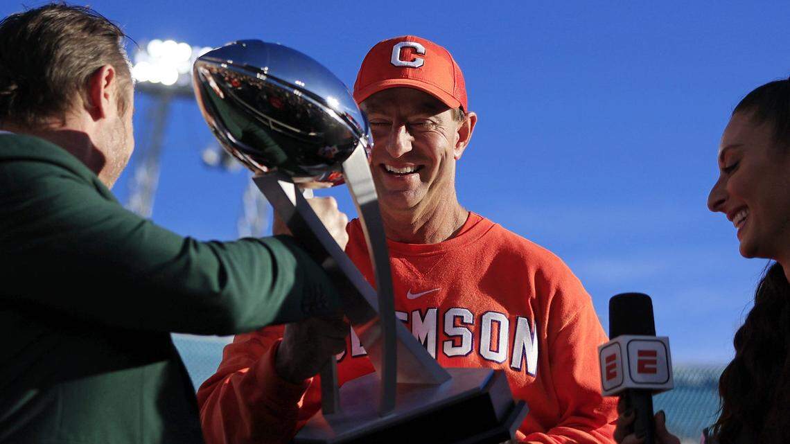 Clemson Tigers head coach Dabo Swinney admires the Ash Verlander Champions Trophy before hoisting it over his head after the game of an NCAA football matchup in the TaxSlayer Gator Bowl Friday, Dec. 29, 2023 at EverBank Stadium in Jacksonville, Fla. The Clemson Tigers edged the Kentucky Wildcats 38-35.