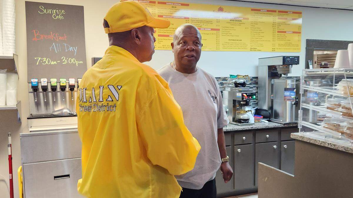 Johnny Davis, right, talks with a member of the Main Street District yellowshirt team on Nov. 21, 2023. Davis recently opened Sunrise Cafe on Main Street.