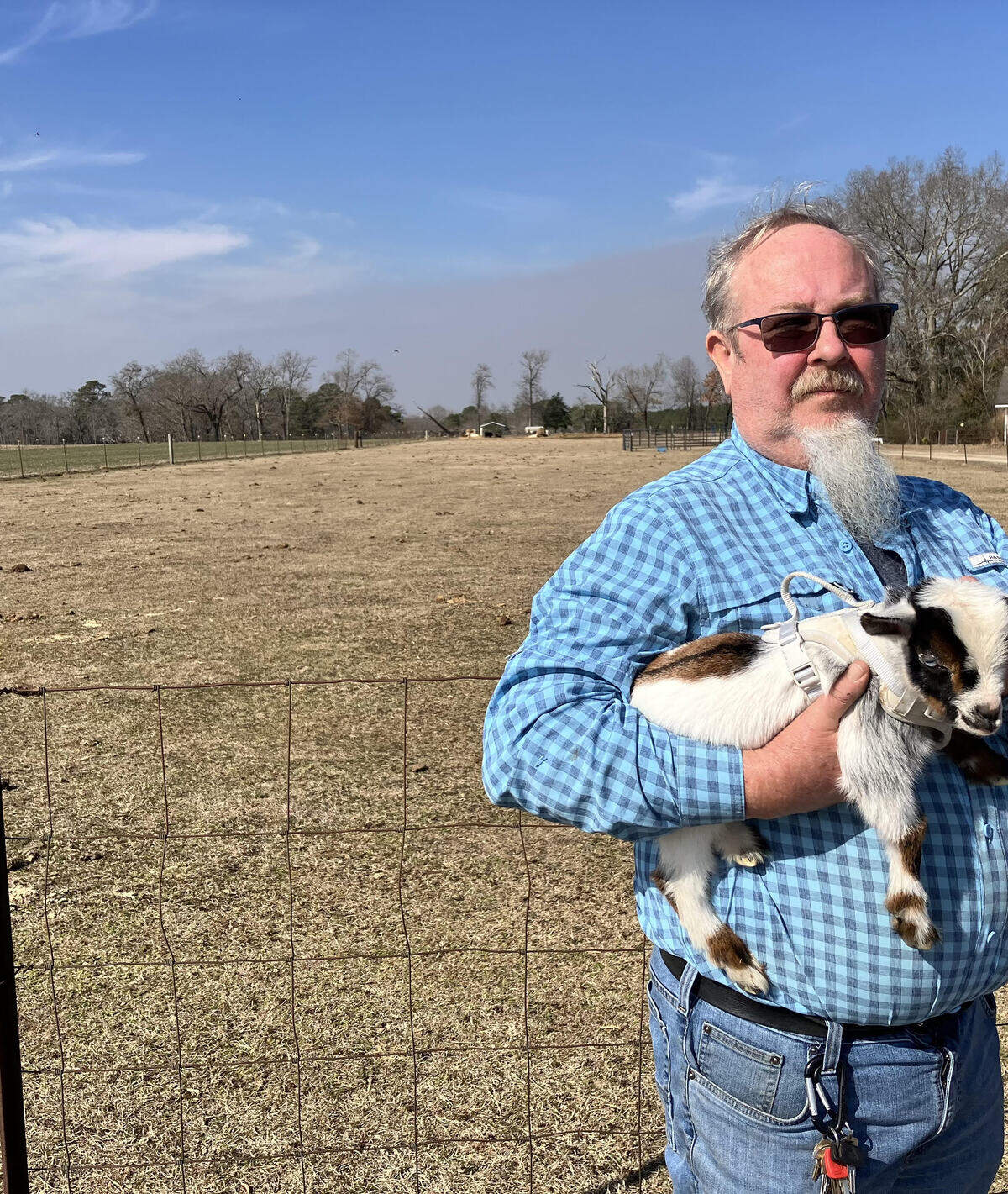 Farmer Robbie O’Neal holds his pet goat Feb. 10 while standing in front of an agricultural field that today is polluted with toxic forever chemicals. The family allowed industrial sludge from a textile plant to be used as a fertilizer after government regulators said it was safe.