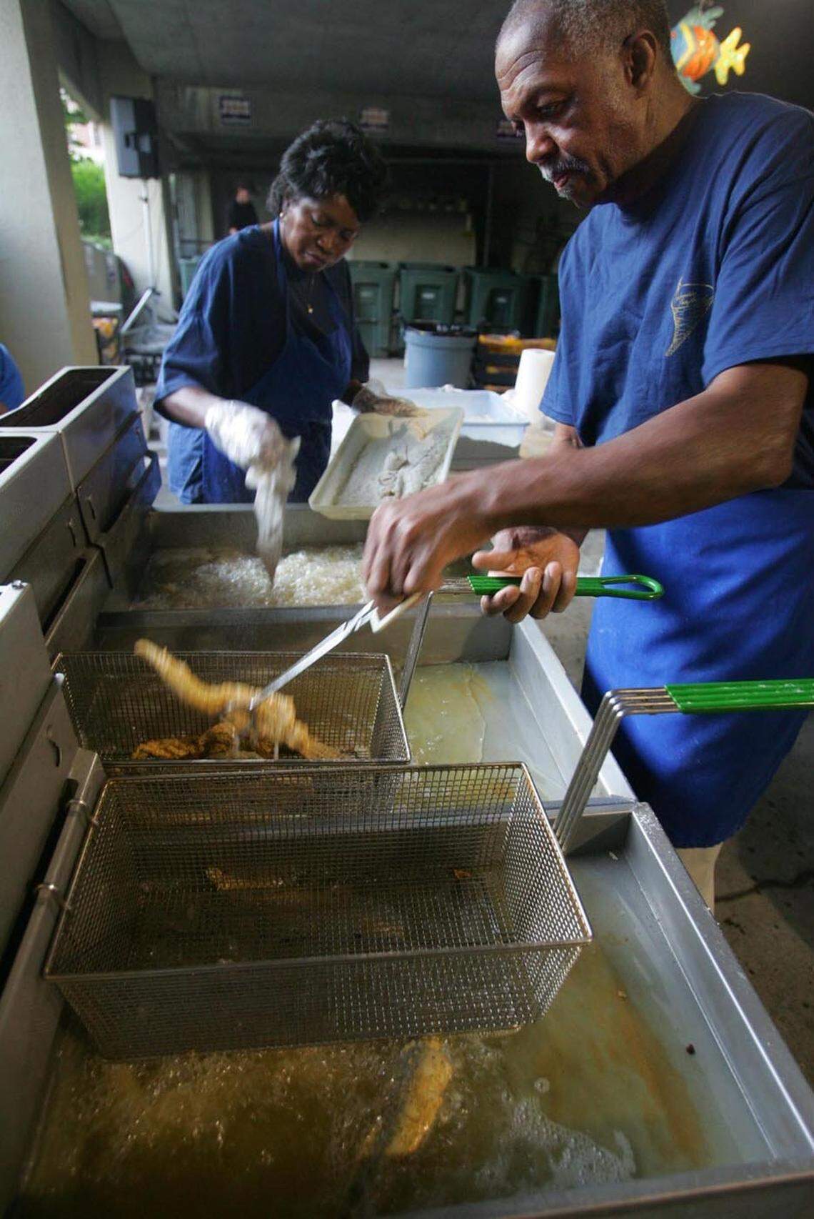 -Lucius Moultrie, right, owner of PalmettoSeafood Company, cooks up some fried fish.