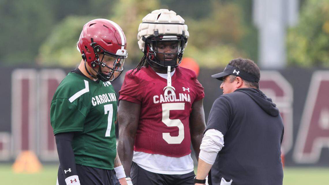 South Carolina quarterback Spencer Rattler (7) and running back Dakereon Joyner (5) speak to offensive coordinator Dowell Loggains during practice on Thursday, August 16, 2023.