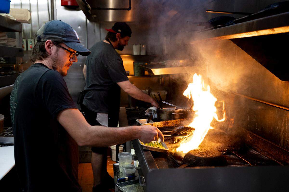 Daniel Whalen, left, prepares steaks on the grill as Dieter Steinborn starts a dish at Saluda’s Restaurant in this 2024 photo.