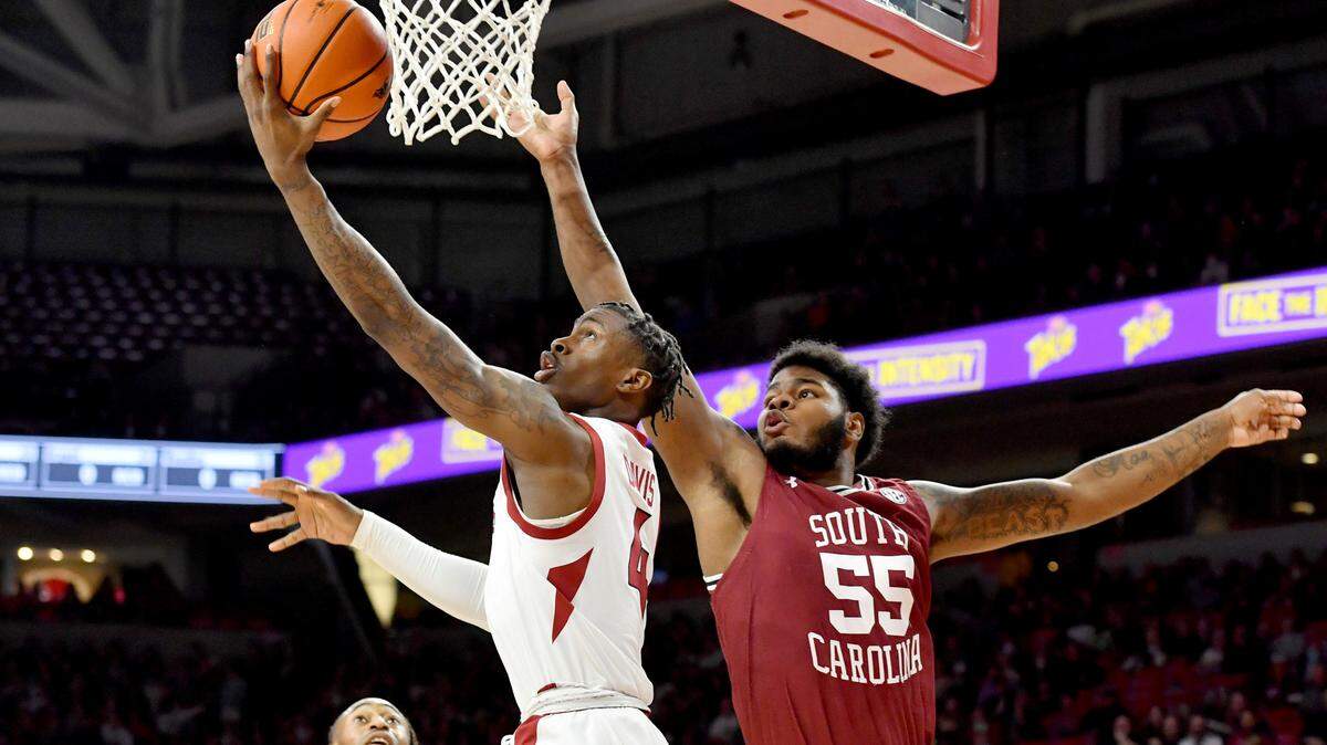 Arkansas guard Davonte Davis (4) drives past South Carolina forward Ta’Quan Woodley (55) to score during the first half of an NCAA college basketball game Tuesday, Jan. 18, 2022, in Fayetteville, Ark.