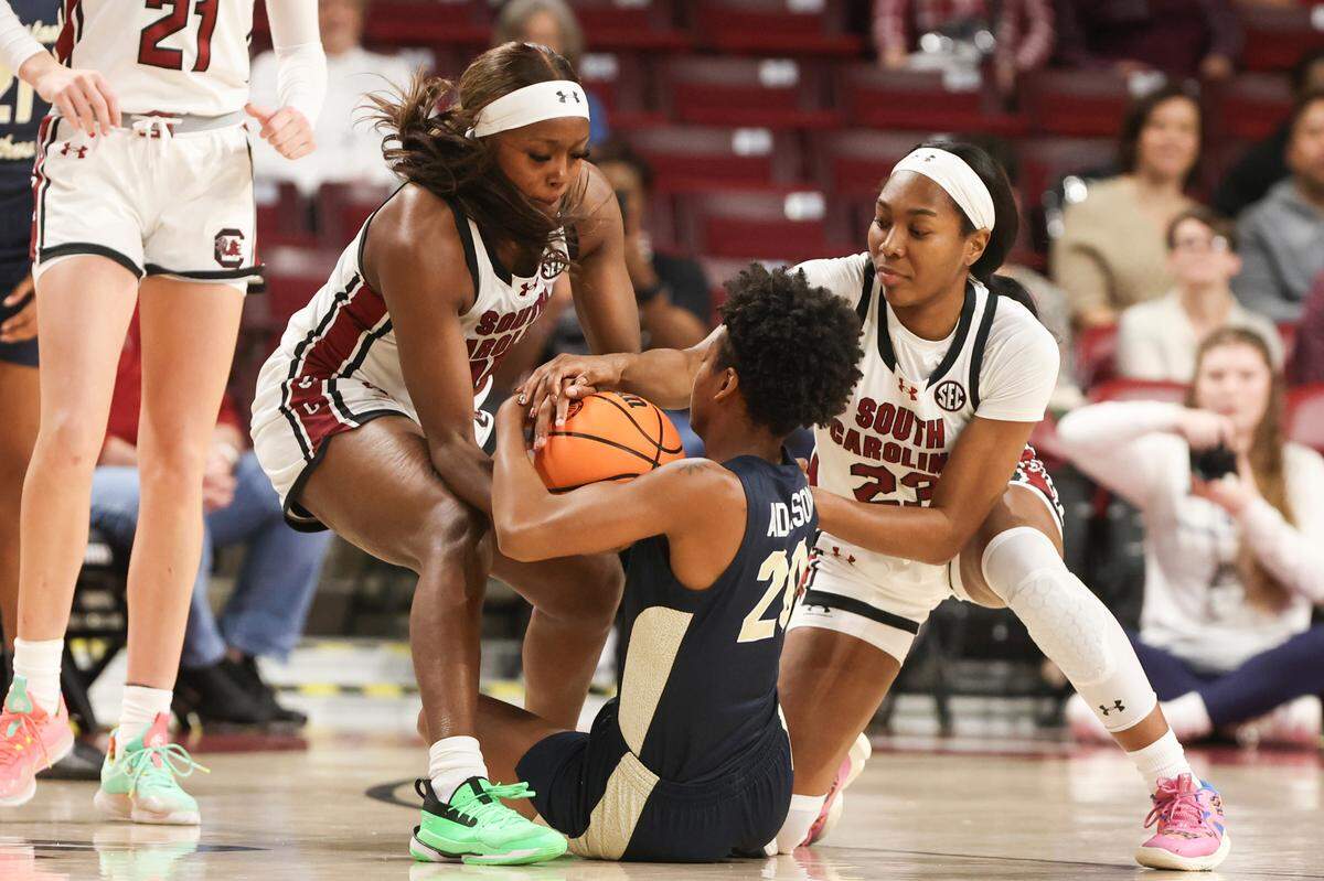 University of South Carolina’s Raven Johnson (25) and University of South Carolina’s Bree Hall (23) grapple with Charleston Southern’s Madison Adamson (20) for a ball during the first half of action in the Colonial Life Arena on Thursday, Dec.19, 2024.