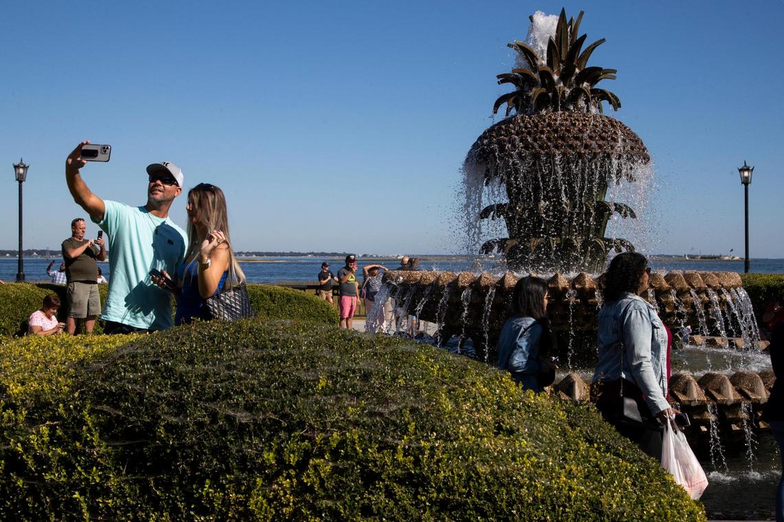 Tourists take photos near the Pineapple Fountain at Joe Riley Waterfront Park in Charleston, South Carolina on Saturday, October 23, 2021.