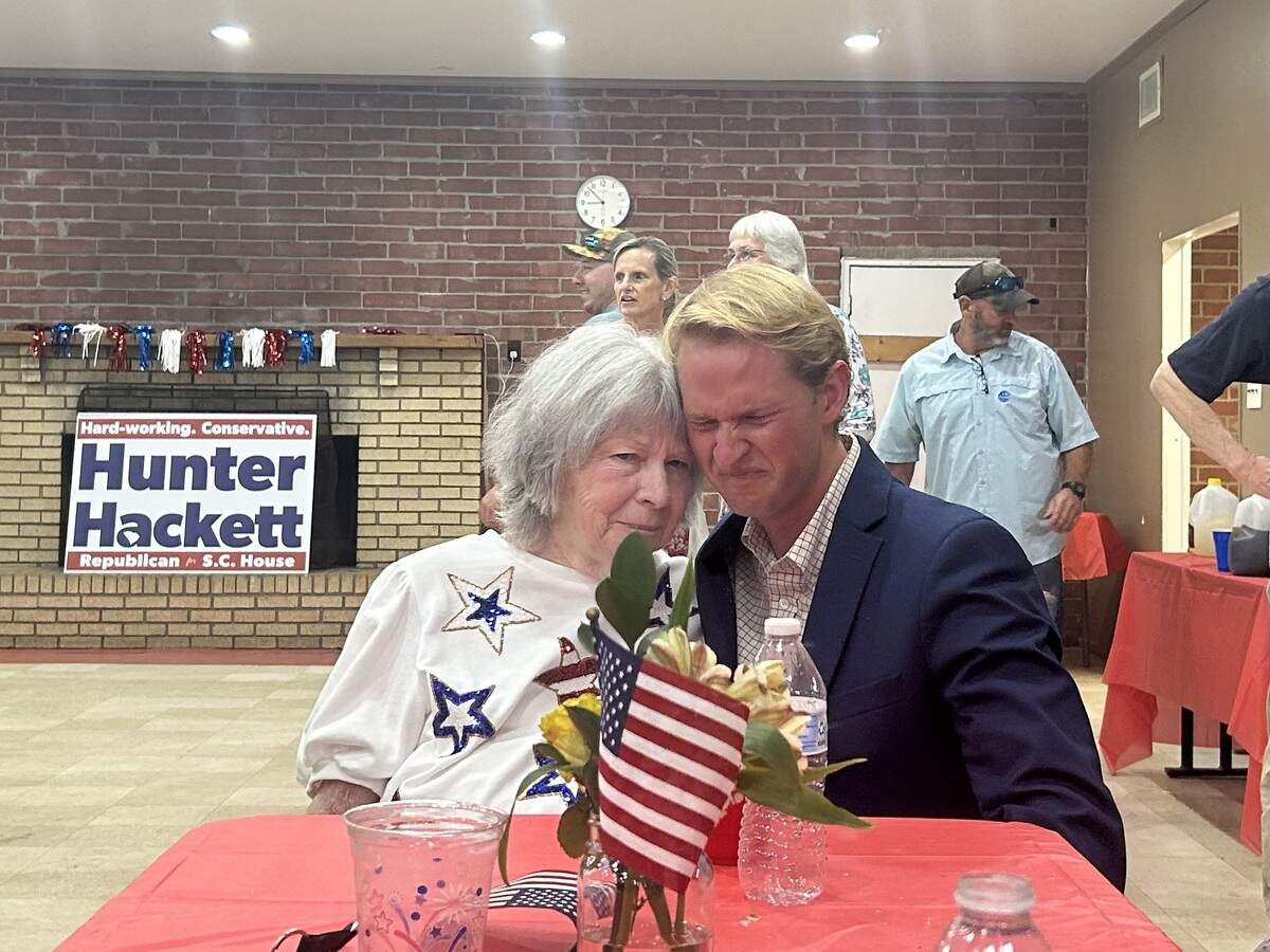 Candidate Hunter Hackett hugs his grandmother at a table.