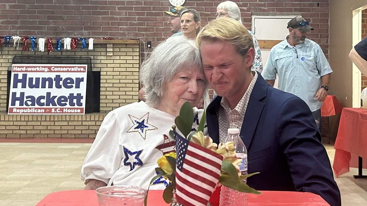 Candidate Hunter Hackett hugs his grandmother at a table.
