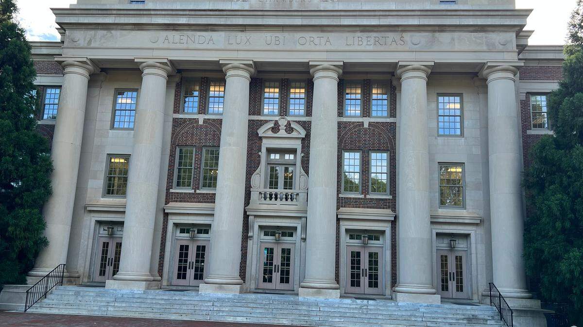 The Chambers building is shown on the campus of Davidson College in North Carolina. The Latin phrase adorning the building translates to “Let learning be cherished where liberty has arisen.”