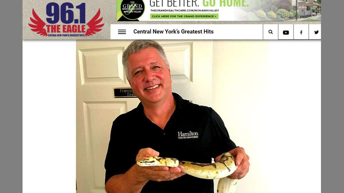 A screenshot shows a member of the Hamilton College staff holding the escaped snake.