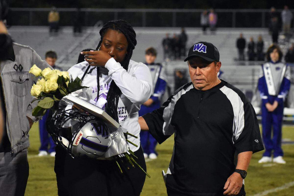 Aphrodesia McKelvey, left, walks off the football field at West Ashley High School’s Wildcat Stadium during the last home game of the 2021 season. Her 15-year-old son, Mikell, was killed on Nov. 26, 2020. His murder is still unsolved.