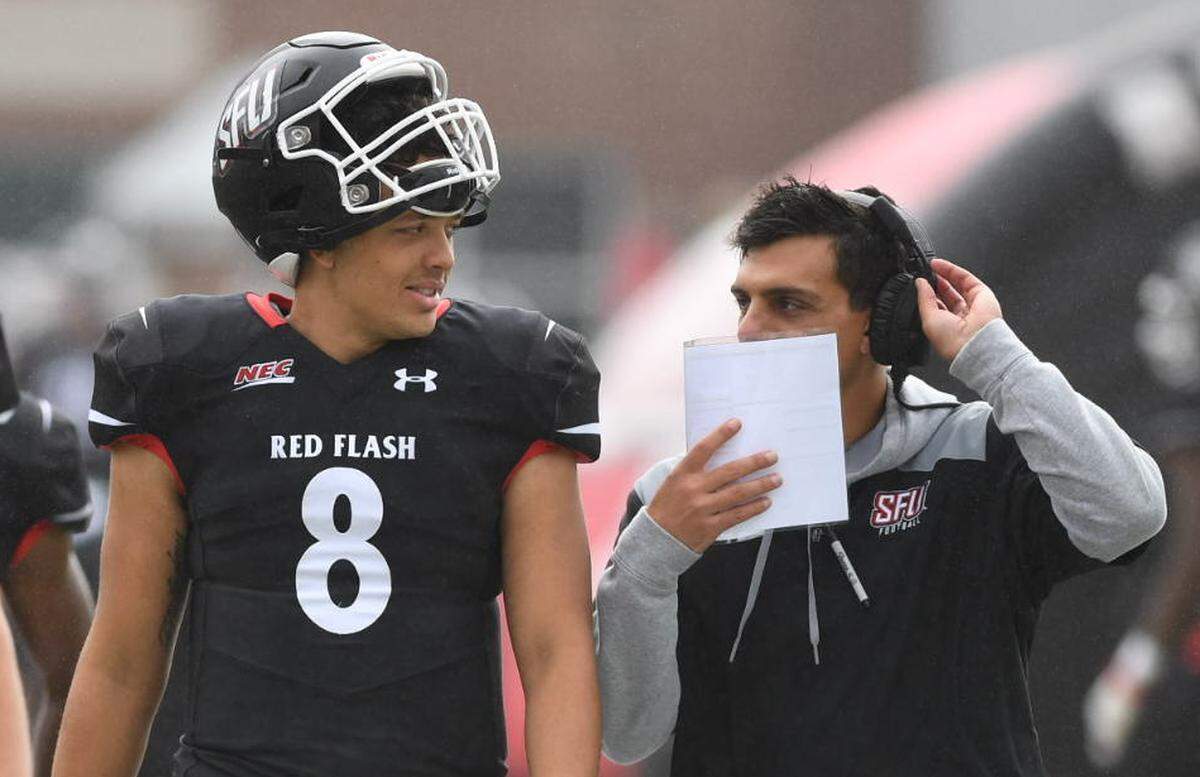 Jason Brown and St. Francis offensive coordinator Marco Pecora chat during a game against Robert Morris. Brown was recruited to St. Francis by Pecora out of Virginia.