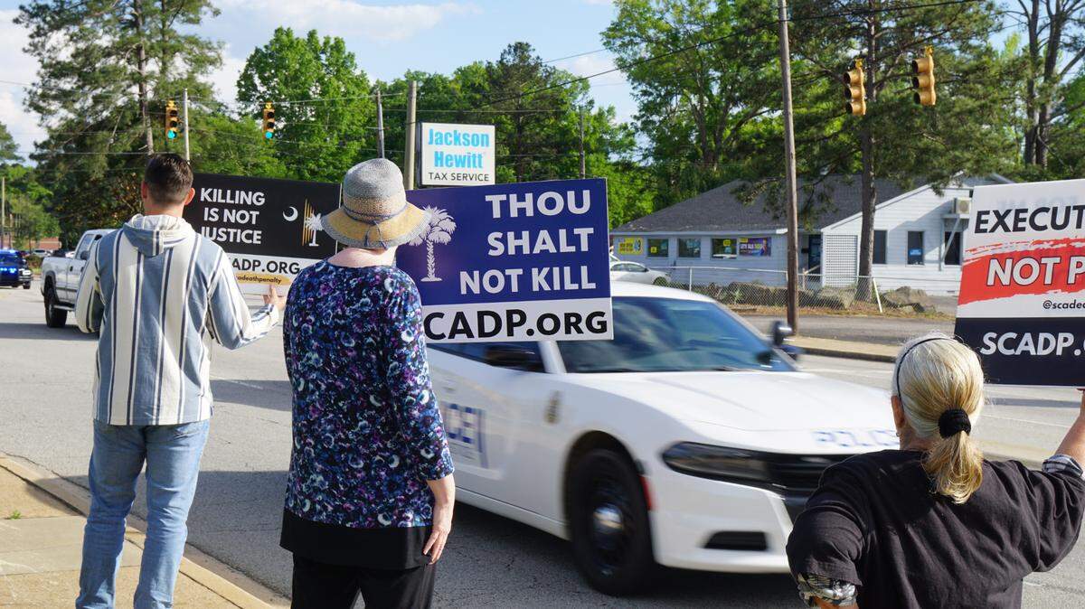 Protesters outside the Broad River Road Correctional Institution, which holds South Carolina’s death chamber, hold up signs protesting the execution of Mikal Mahdi on Friday.