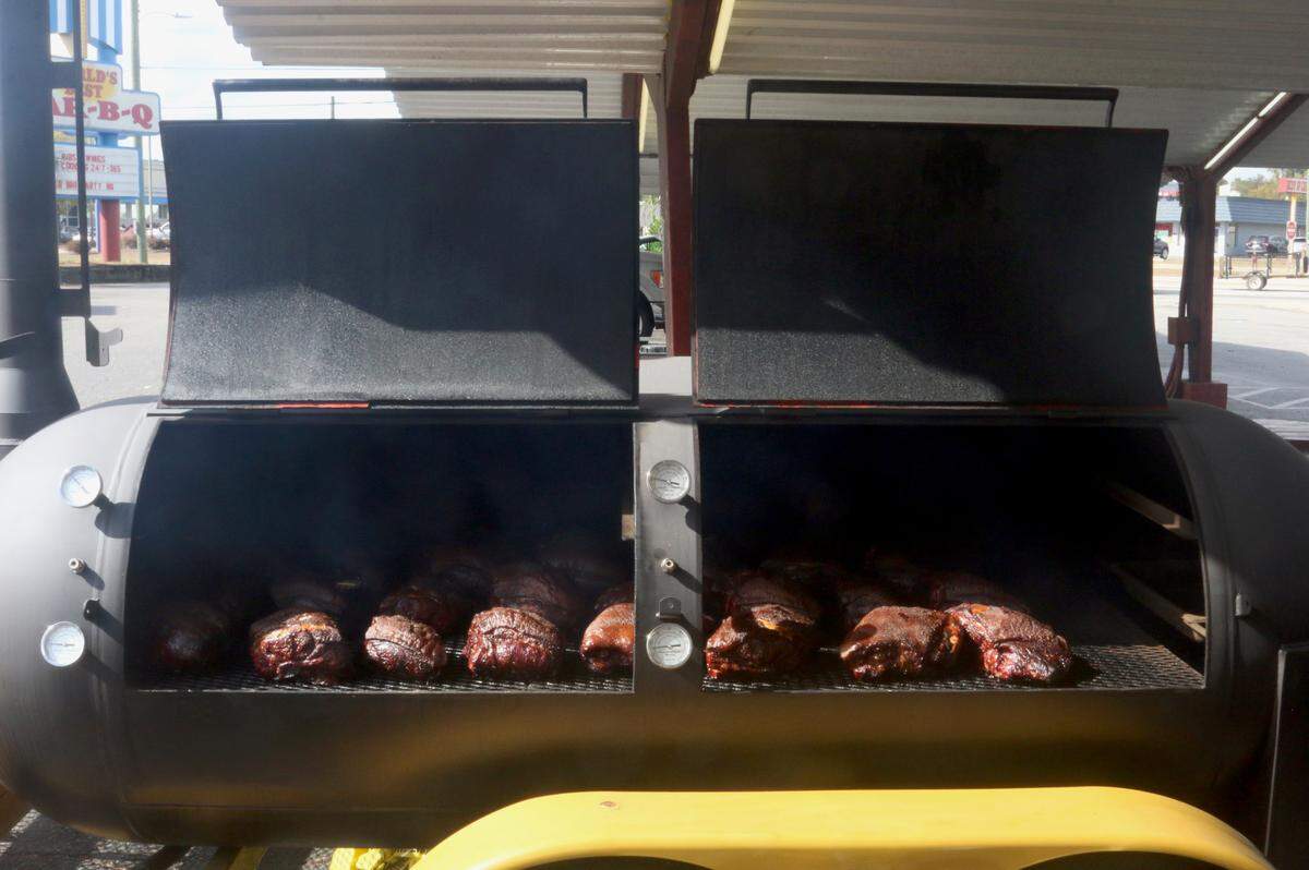 Boston butts cook on a smoker Maurice’s Piggie Park BBQ pitmaster Paul Bessinger borrowed from a cousin on Nov. 1, 2024. The West Columbia restaurant has temporarily moved smokers under the awnings in its parking lot to start cooking again after its cooking facility was lost to a fire last month.