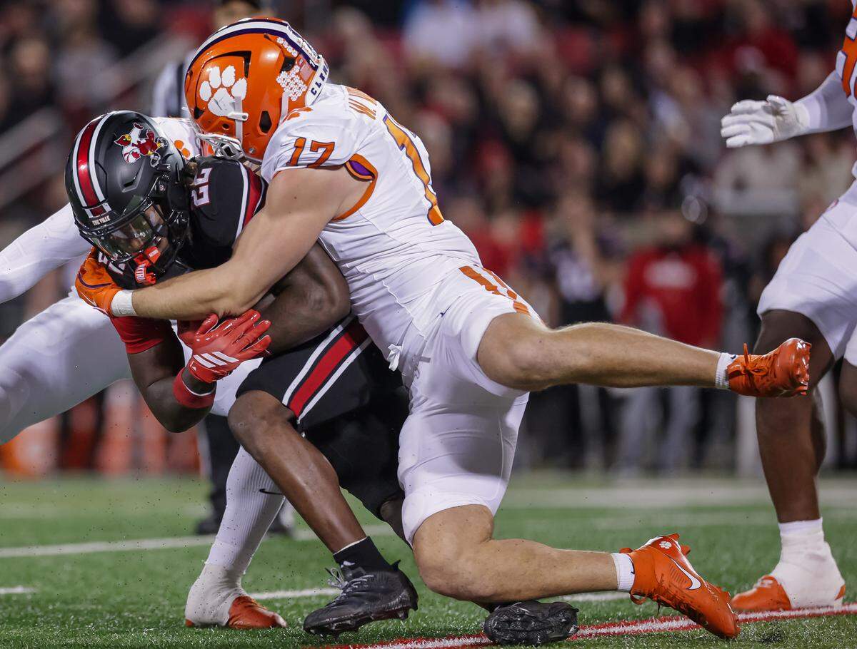 Keyjuan Brown #22 of the Louisville Cardinals is tackled by Wade Woodaz #17 of the Clemson Tigers during the first half of the NCAA football game between the Louisville Cardinals and the Clemson Tigers at L&N Federal Credit Union Stadium on November 14, 2025 in Louisville, Kentucky.