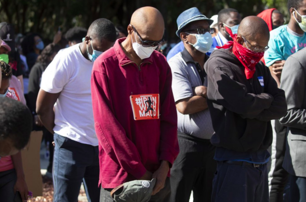 People pray during a rally to protest the shooting of Ahmaud Arbery, an unarmed black man Friday, May 8, 2020, in Brunswick Ga. Two men have been charged with murder in the February shooting death of Arbery, whom they had pursued in a truck after spotting him running in their neighborhood. (AP Photo/John Bazemore)pursued in a truck after spotting him running in their neighborhood.