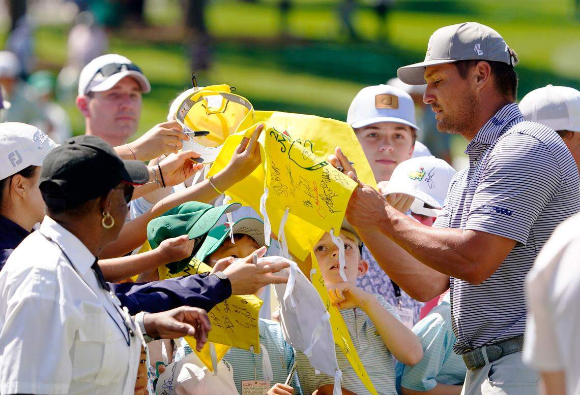 Bryson DeChambeau signs autographs for young patrons Monday at the practice facility during a practice round for the Masters Tournament golf tournament at Augusta National Golf Club.