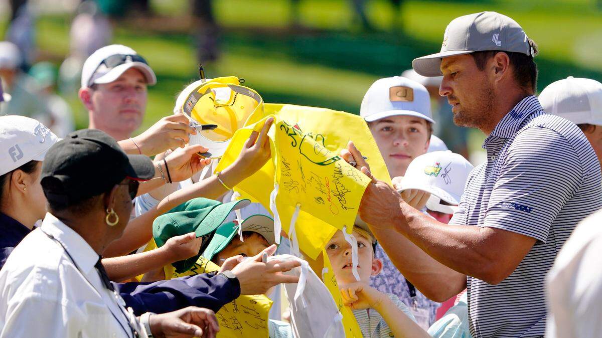 Bryson DeChambeau signs autographs for young patrons Monday at the practice facility during a practice round for the Masters Tournament golf tournament at Augusta National Golf Club.