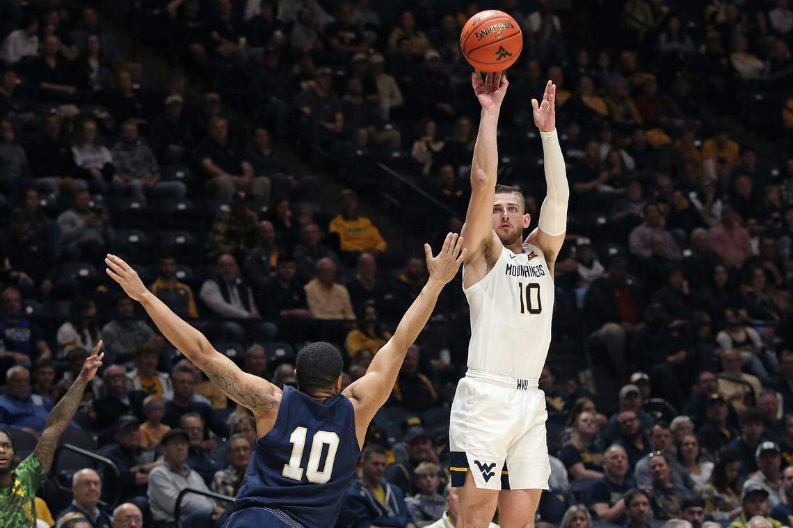 West Virginia guard Erik Stevenson (10) shoots while defended by Navy guard Christian Jones (10) during the second half of an NCAA college basketball game in Morgantown, W.Va., Wednesday, Dec. 7, 2022.