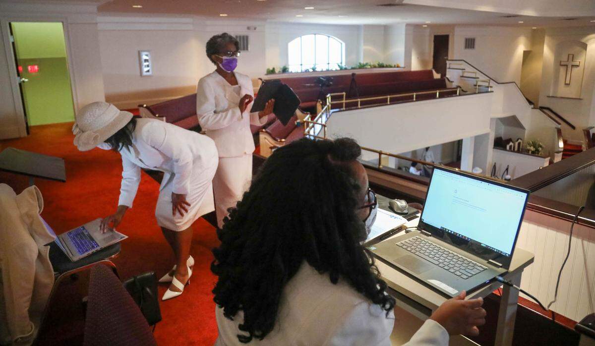 There is a flurry of activity in the balcony at Progressive Church of our Lord Jesus Christ as the internet goes down moments before a funeral service. With coronavirus protocols in place large groups cannot gather at the church so all services are recorded and live-streamed.