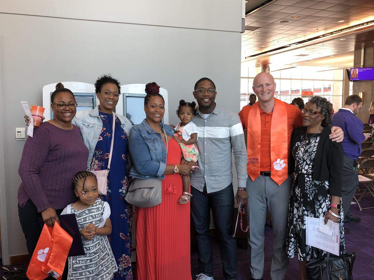 Terrence Oglesby (orange shirt) poses for a photo with Demontez Stitt's family after Stitt received his degree posthumously on Wednesday.
