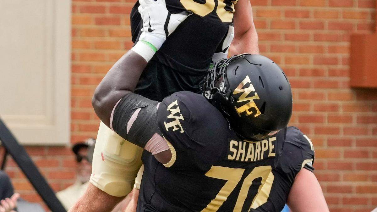 Wake Forest Demon Deacons offensive lineman Nick Sharpe (70) lifts up running back Tate Carney (30) after his score against the Vanderbilt Commodores during a 2023 game.