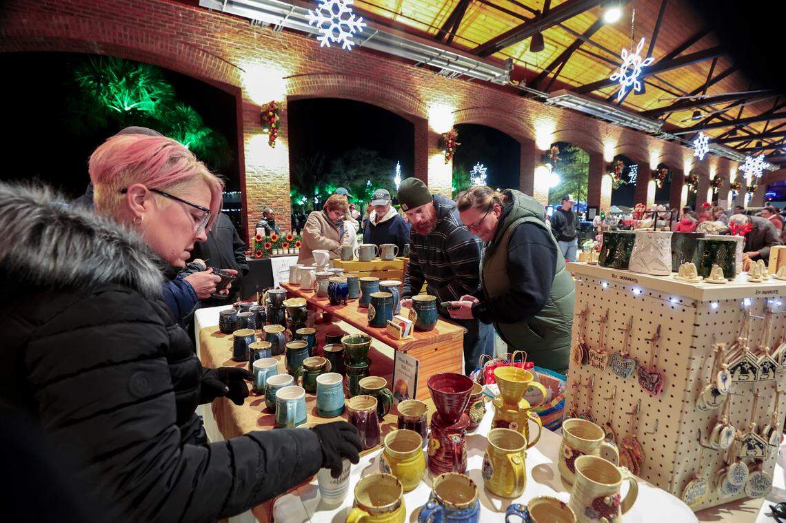 Cinnamon Larkin shops at Sunset Studio Pottery in the market at Lexington’s Icehouse Amphitheater. The crafts market was set up for the Christmas Carolighting Ceremony at the Icehouse Amphitheater on Friday Dec. 6, 2024.