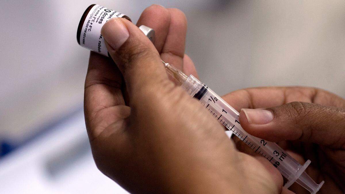 In this file photo, a health worker prepares a syringe with a vaccine against measles.