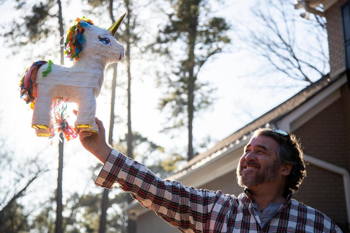 Ed McDonnell poses for a portrait with a unicorn piñata at his home in Columbia, South Carolina on Thursday, January 14, 2021. McDonnell got the idea after seeing his daughter’s unicorn print shoes, and wanted to surprise her with something special.