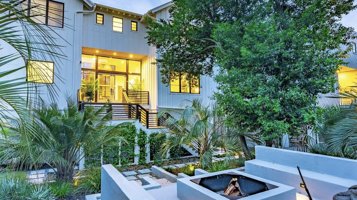 The landscaping features bamboo, olive trees, and Star Jasmine surrounding an entertainment area.