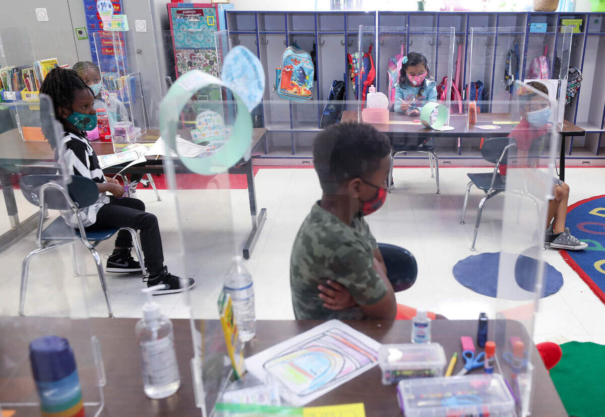 First-graders sit in a classroom on Wednesday, Aug. 18, 2021, the first day of school at A.C. Moore Elementary School. Social distancing, masks and plexiglass dividers help prevent the spread of The Coronavirus.