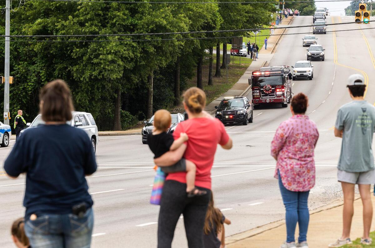 People watch a procession for Firefighter James Muller, who was killed in a structure fire Friday, in Irmo, South Carolina on May 31, 2023. Law enforcement and public safety agencies from around the region followed Muller’s fire company to Riverland Hills Baptist Church.