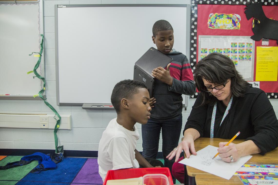 Diana Pearson helps her student Tykevious Bryant, 10, left, finish a drawing for a story his writing for class as Javarion Slappy, 10, stands behind them. Pearson teaches the fifth grade at Lakeview Elementary School and will visit her students on the weekend during her days off.