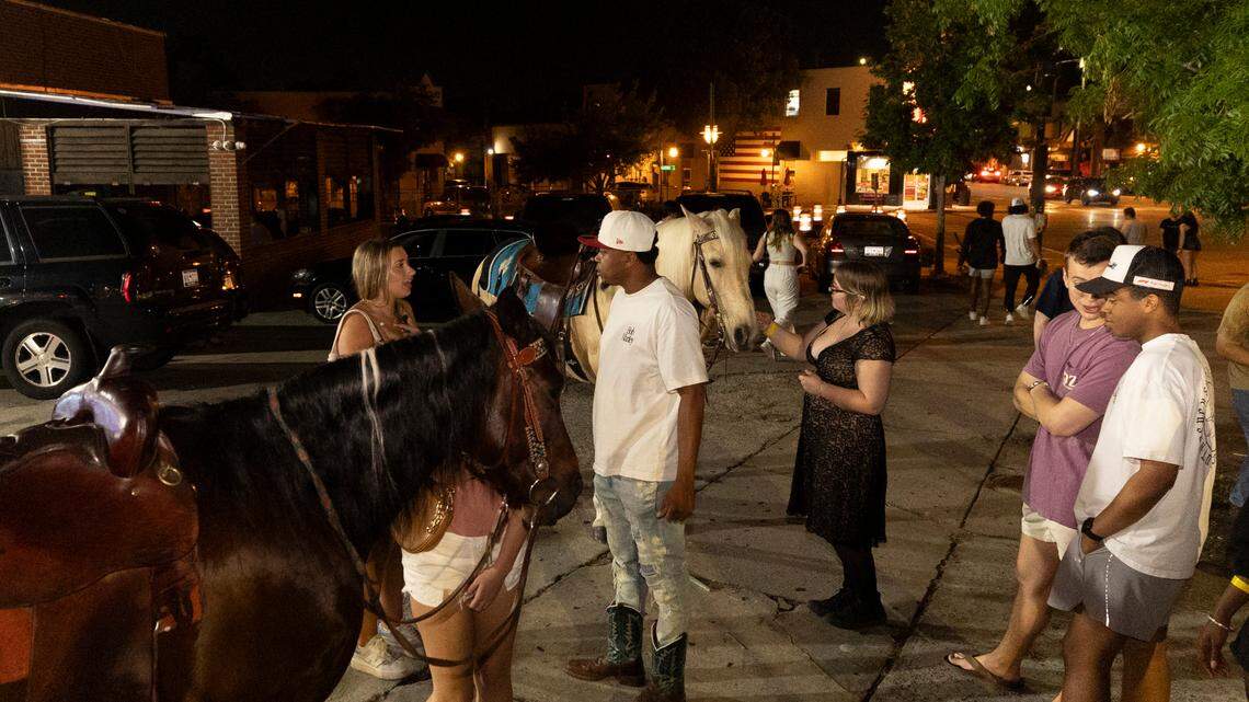 Five Points patrons mingle with horses brought to the commercial and retail village by Stephen Harmon on Wednesday, May 10, 2024.