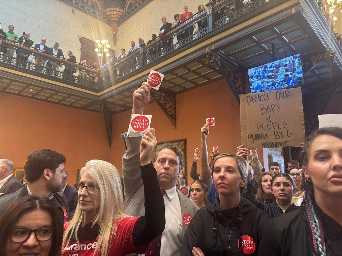 Demonstrators hold up signs and stickers against a tort reform package on Wednesday, March 5, 2025 at the South Carolina State House during a news conference in favor of the tort reform package.