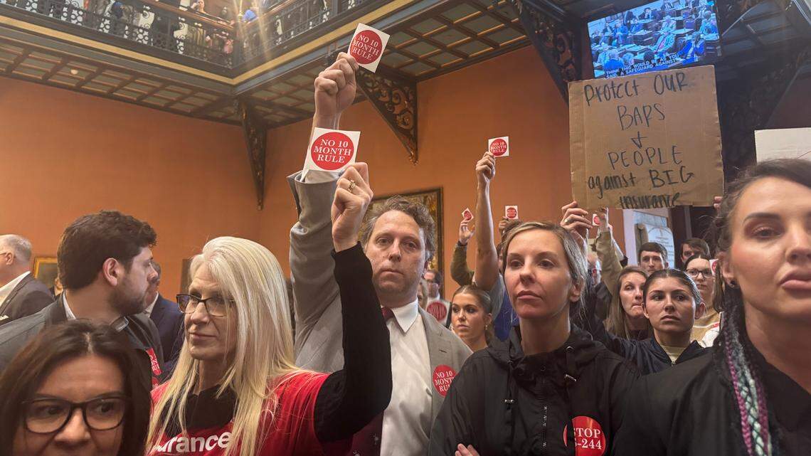 Demonstrators hold up signs and stickers against a tort reform package on Wednesday, March 5, 2025 at the South Carolina State House during a news conference in favor of the tort reform package.