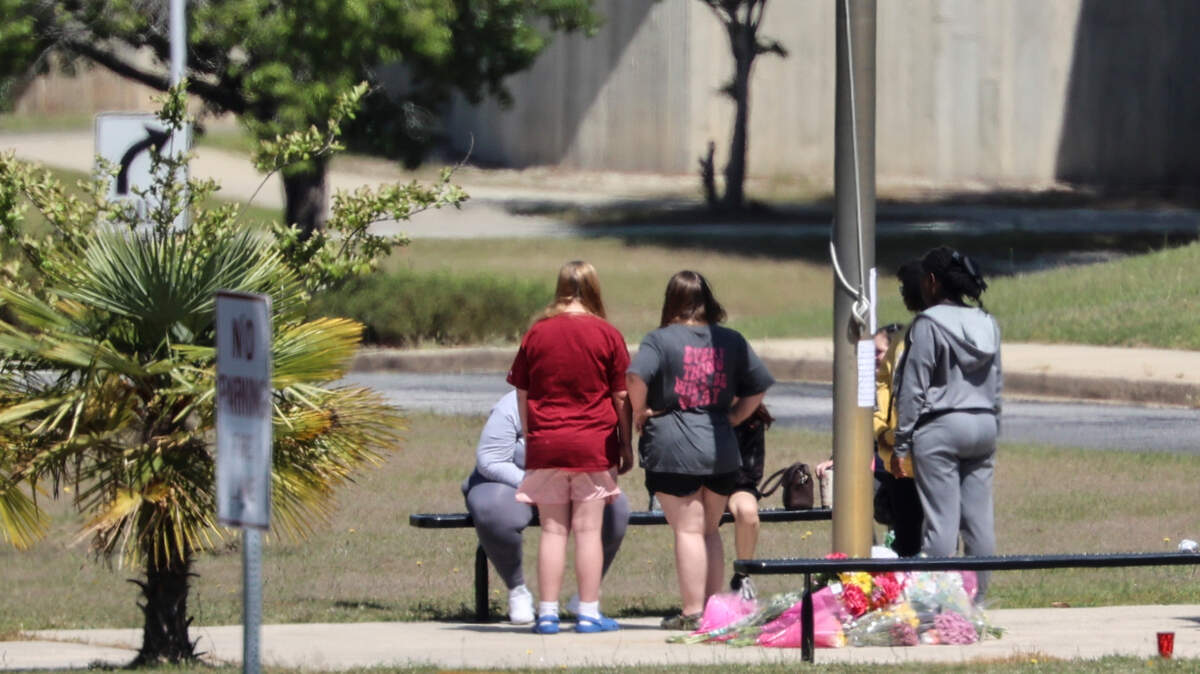People gather around a memorial at Pine Ridge Middle School a day after a school bus carrying students returning from a field trip overturned in Chester County. One student died of his injuries and 21 were sent to the hospital.