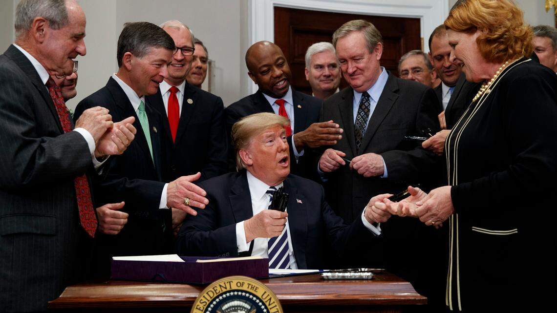 President Donald Trump hands out pens after signing the "Economic Growth, Regulatory Relief, and Consumer Protection Act," in the Roosevelt Room of the White House, Thursday, May 24, 2018, in Washington.