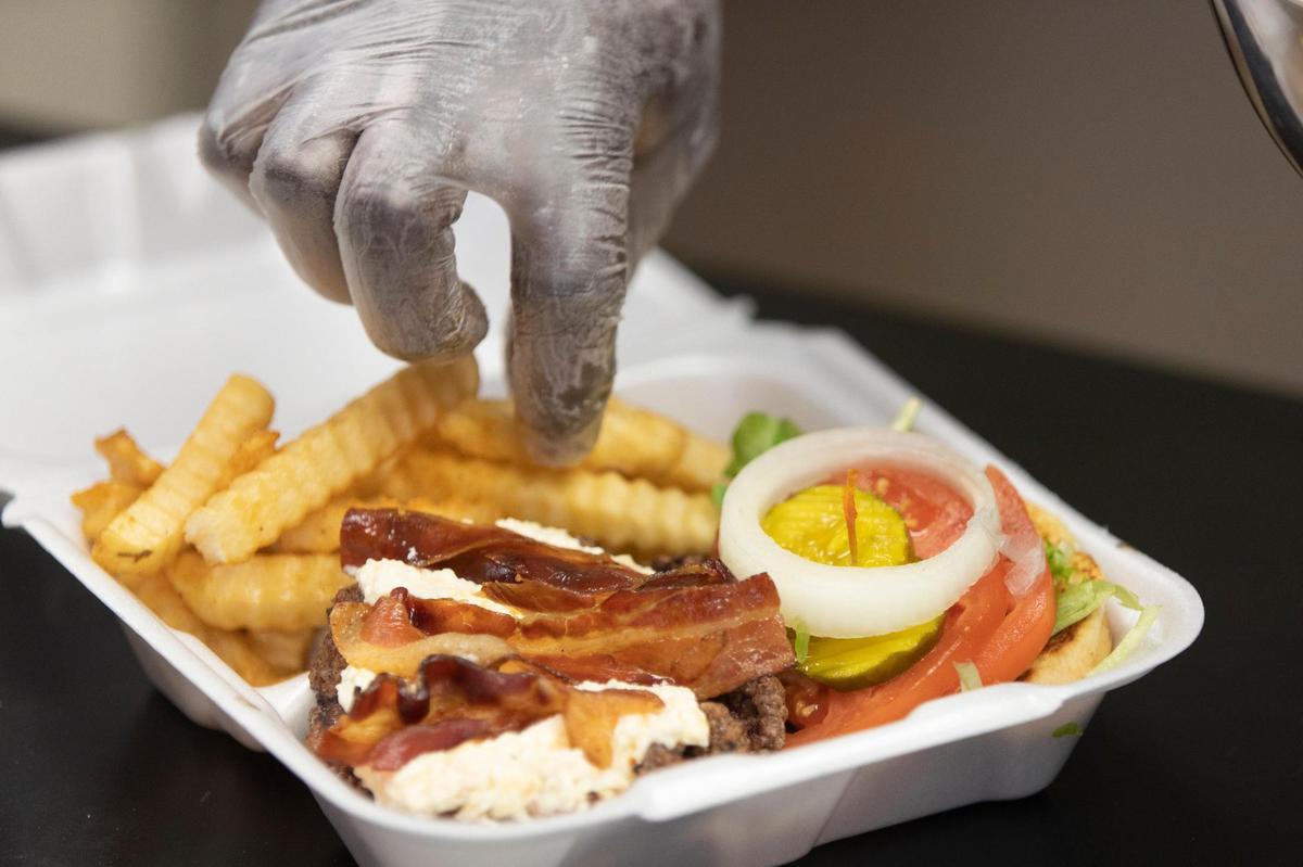 Kevin Rountree places French fries in a box with a bacon jalapeño pimento cheese burger at Roy’s Grille, located at a gas station in Lexington, South Carolina on Friday, January 7, 2022.