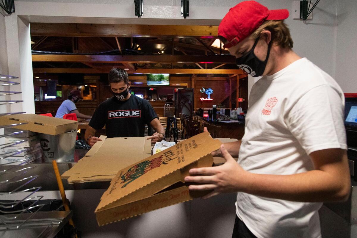 Workers at The Village Idiot in Five Points fold boxes in preparation of opening on Tuesday, September 22, 2020. The restaurant is celebrating 30 years of serving pizza in Five Points while also adapting to the coronavirus.