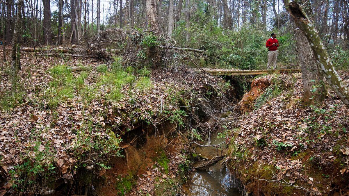 Chapin High School principal Akil Ross stands on a small bridge above a creek that is the center of a controversy halting renovation on the school. Lexington-Richland 5 school board member Kim Murphy is seeking to overturn a plan approved last spring by state environmental officials allowing the field to be extended over a section of the creek on the edge of the school campus.