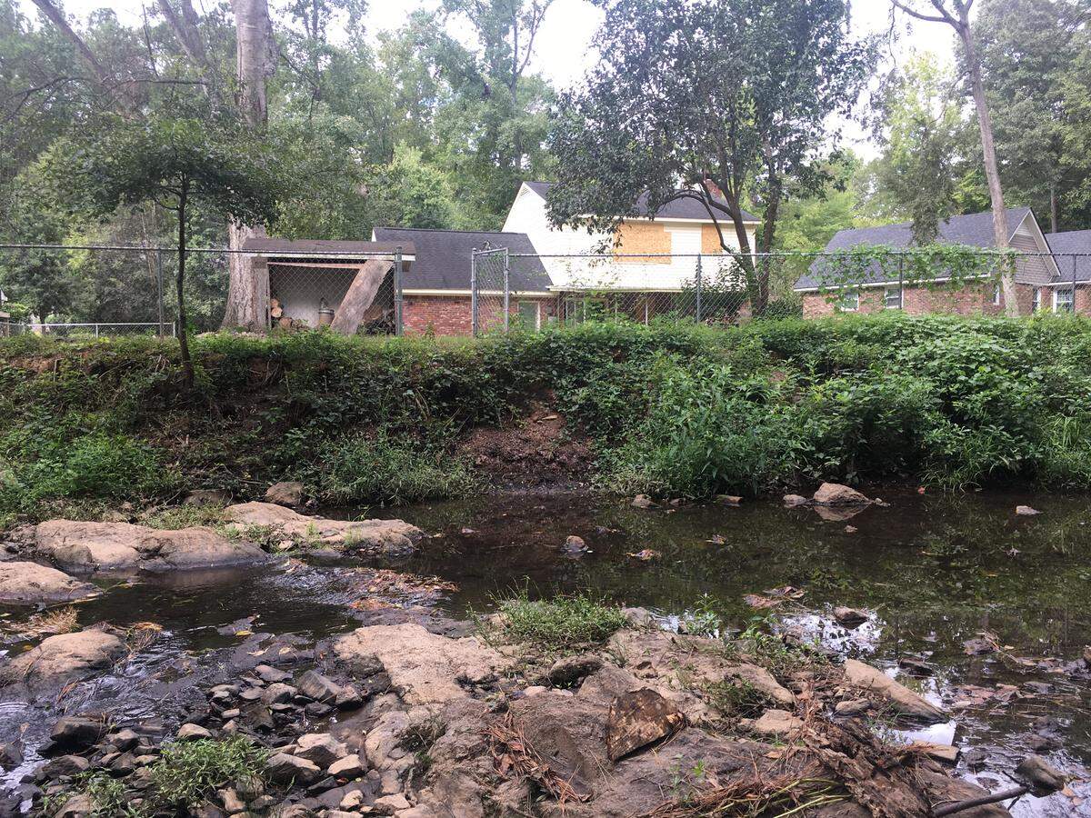 Rawls Creek spilled over into homes in the 2015 flood, one of which is still boarded up and abandoned from damage it sustained three years ago.