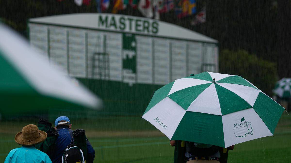 Spectators leave the course in a downpour after play was suspended for inclement weather during the third round of the Masters golf tournament on Saturday, April 10, 2021, in Augusta, Ga. (AP Photo/Charlie Riedel)