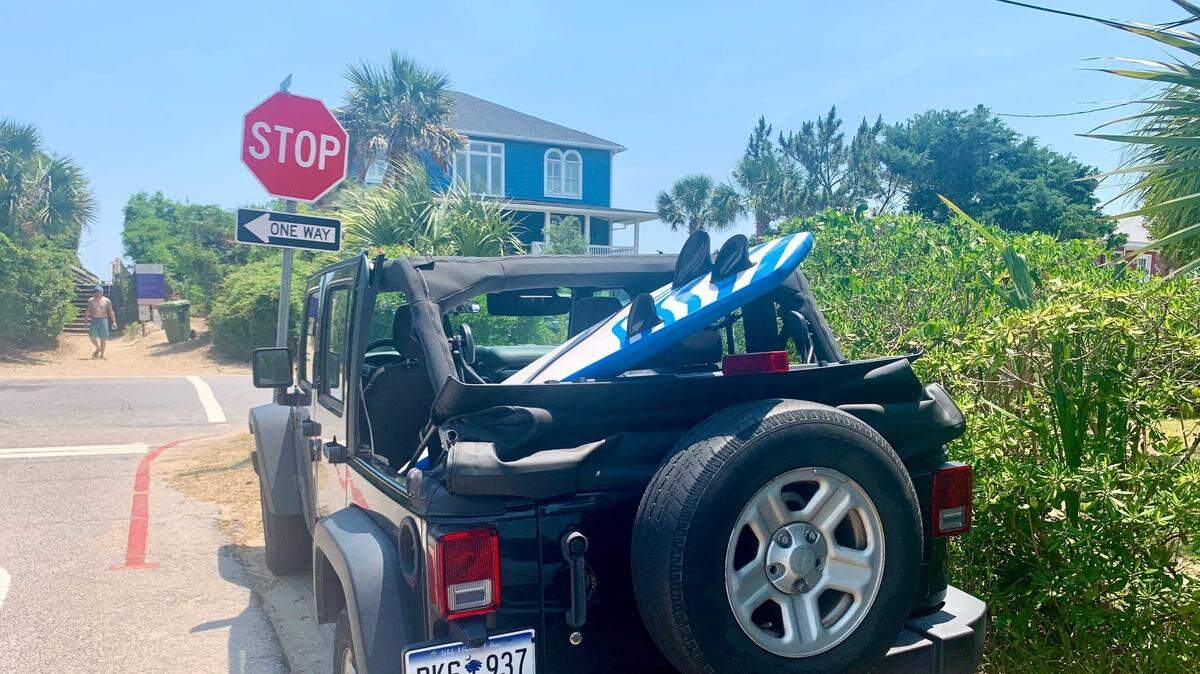 Parked on a side street with a surfboard in the back, a Jeep follows the parking rules at Folly Beach on May 24, 2021. The beach community is one of three major beaches in the Charleston area that will see tourists and locals rushing to its beaches this summer.