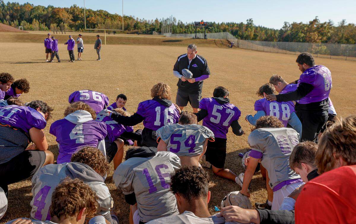 Walhalla football coach Padgett Johnson prays with his team before practice at the school. Johnson has volunteered to coach the 3-A Razorback football team for the past seven seasons.