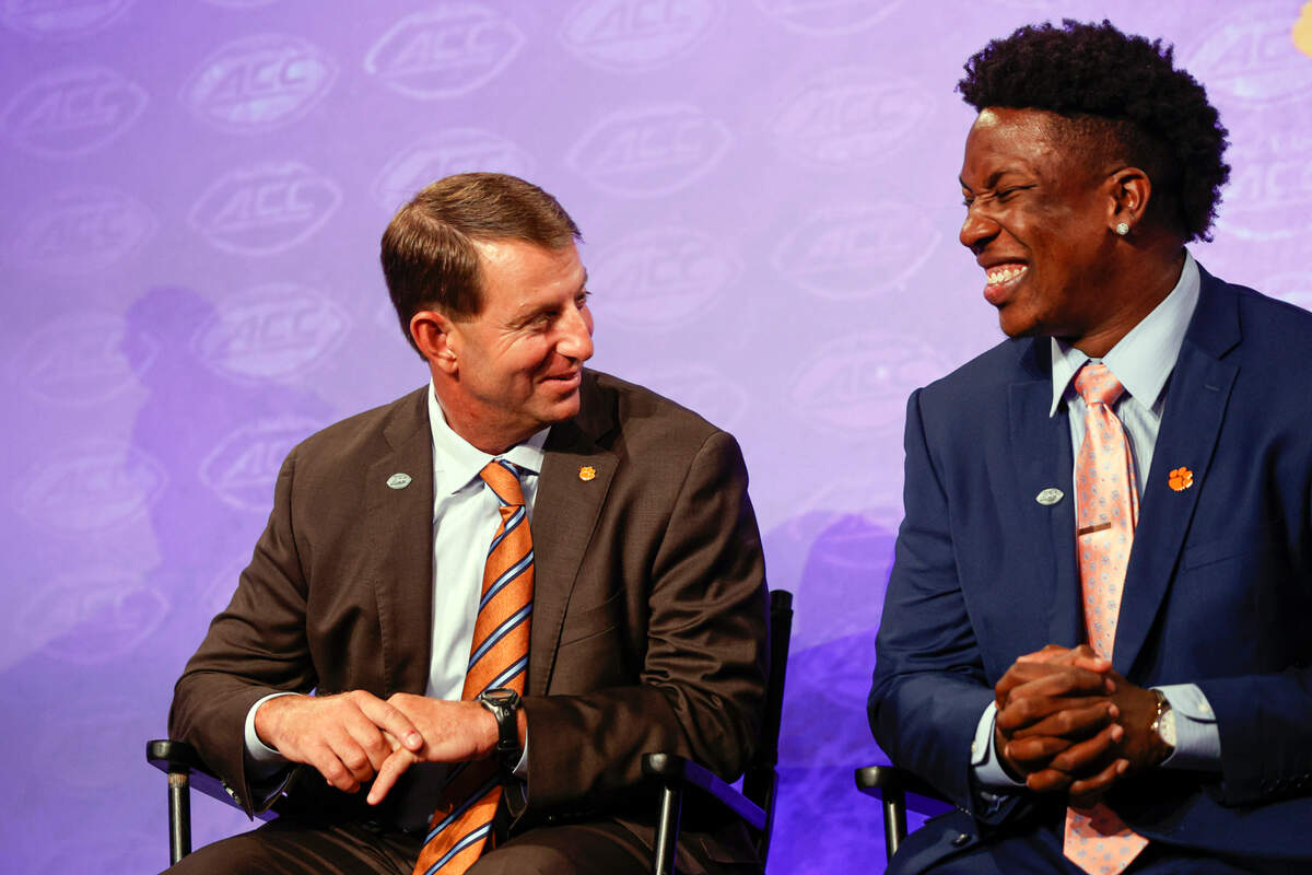 Clemson head coach Dabo Swinney, left, laughs with defensive end K.J. Henry at the NCAA college football Atlantic Coast Conference Media Days in Charlotte, N.C., Wednesday, July 20, 2022. (AP Photo/Nell Redmond)