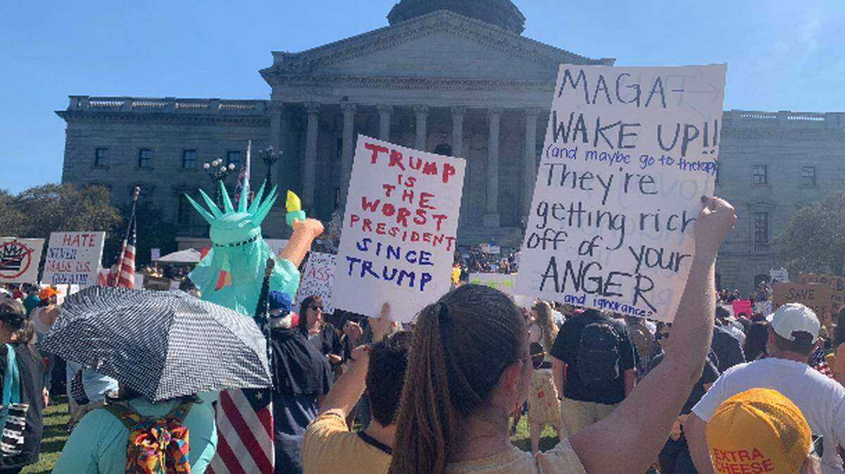 Protesters wave signs at the ‘No Kings’ rally in Columbia, Saturday October 18, 2025. The rally was among multiple protests nationally over President Donald Trump’s policies.