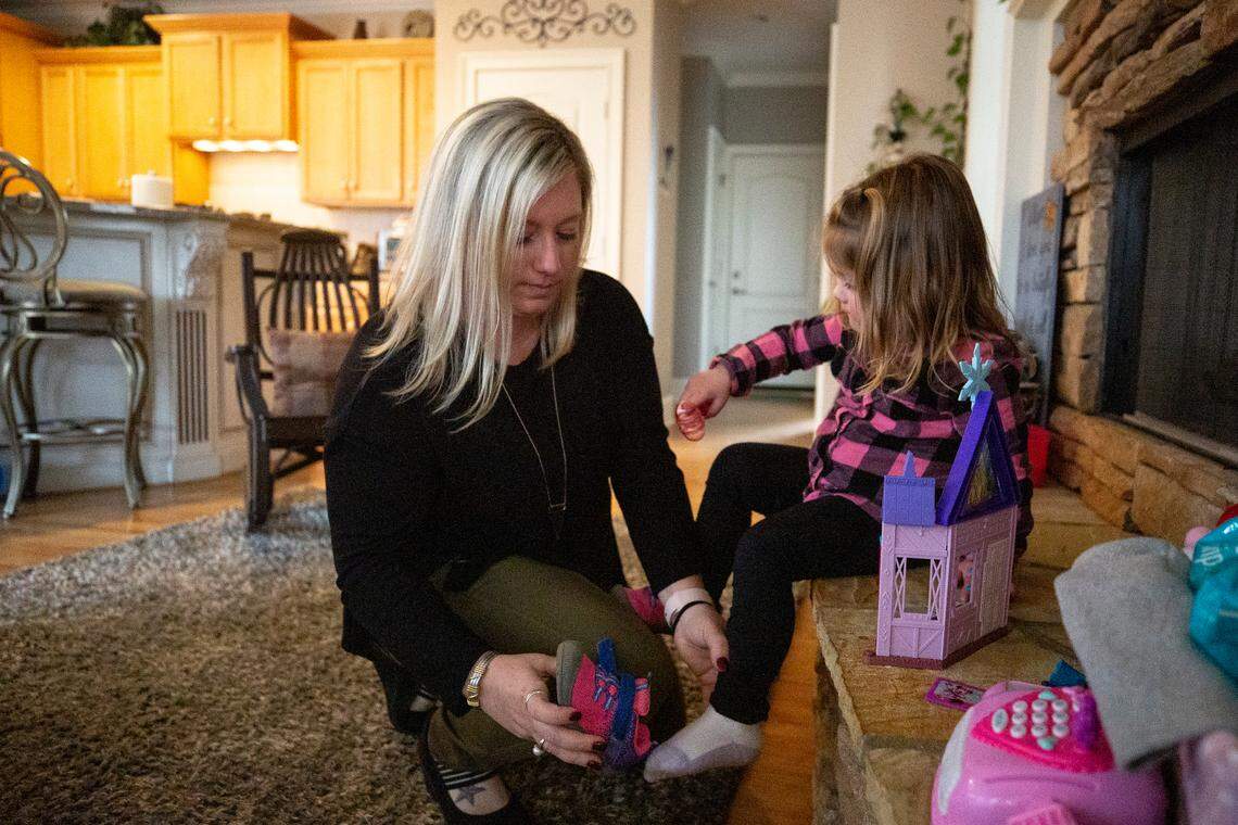 Kerri Gray puts shoes on her daughter, Bailey, 2, before heading to the backyard. In 2013, Gray’s son, Jackson, died from suffocation by bedding at 12 weeks old while staying in a home day care.