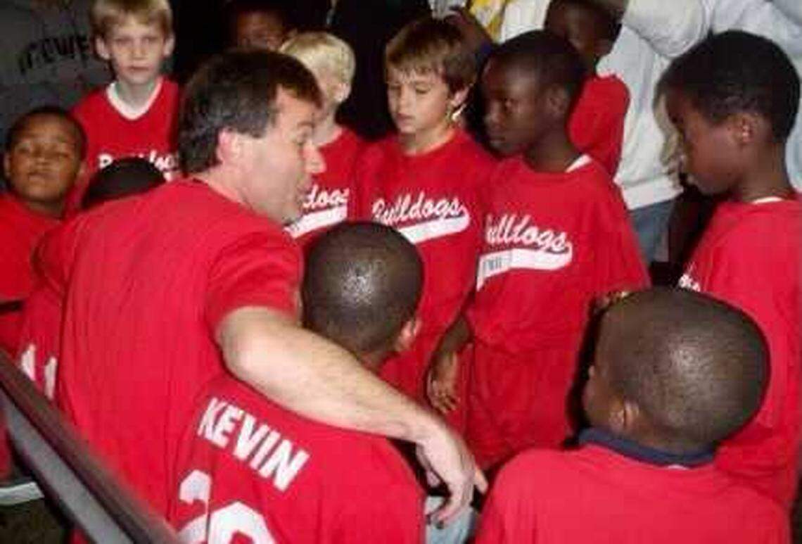 Youth football coach Derek Sills with his his arm around 7-year-old Kevin Harris.