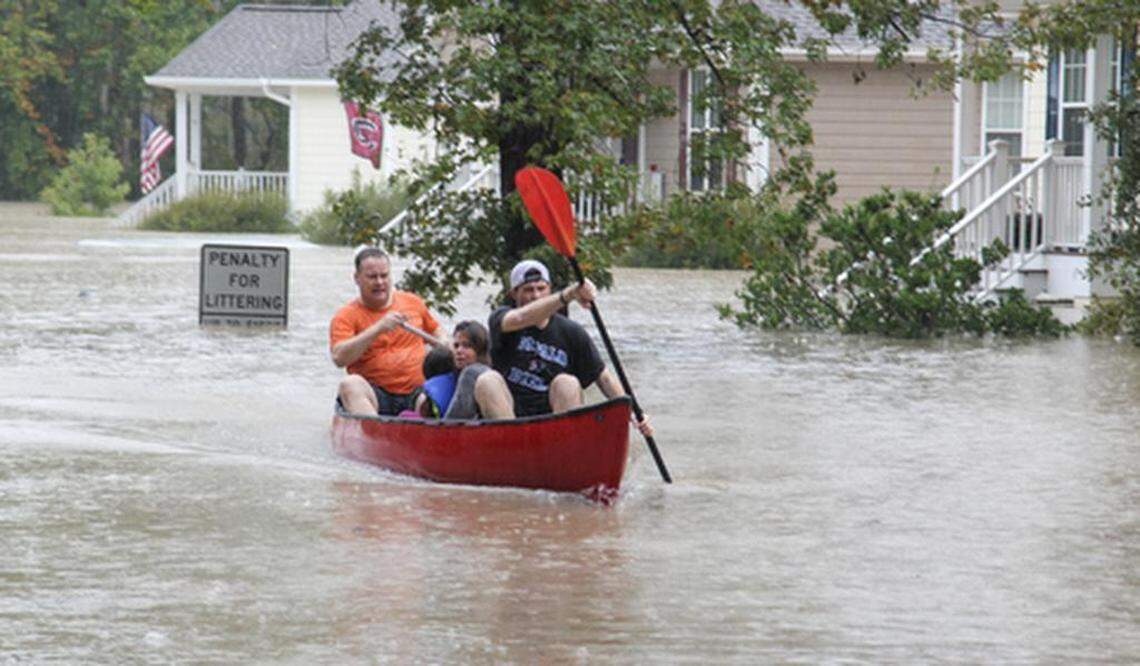 John Wienges, front, and Will Lenski paddle a canoe with Angela and Logan Smith, 7, who they rescued from their flooded house on Timberlane Drive near Gills Creek. The river flooded homes along Timberlane Drive and Whispering Pines Circle caused by heavy rains from Hurricane Joaquin on Oct. 4, 2015.